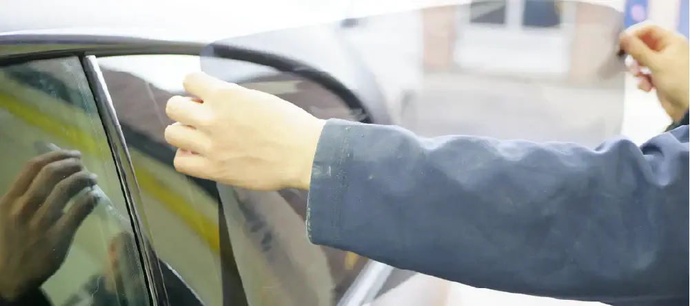 Close up of someone fitting pre cut car window tint to a side window