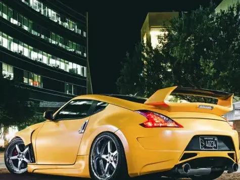 Oracal matte safron yellow wrapped sports car with a large spoiler on a city street at night