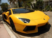 Oracal 970-223M matte safron yellow  wrapped sports car parked on a street with palm trees and buildings in the background
