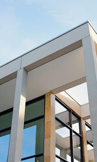 Modern building facade with glass and concrete structure against a clear blue sky.