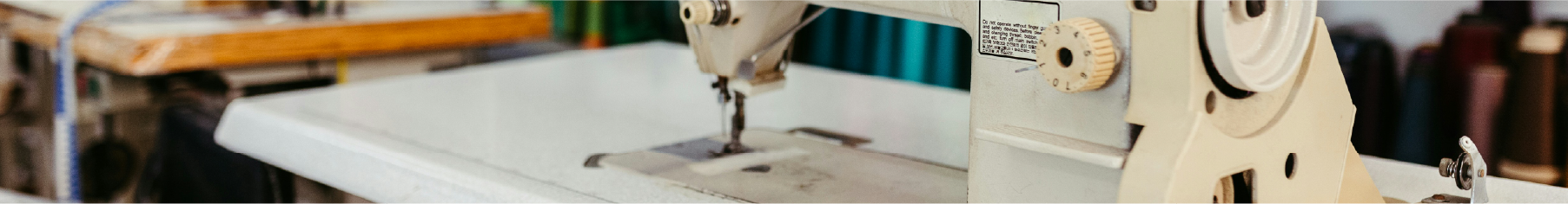 Close up of a sewing machine with fabric behind it to represent fabric vinyl wrap