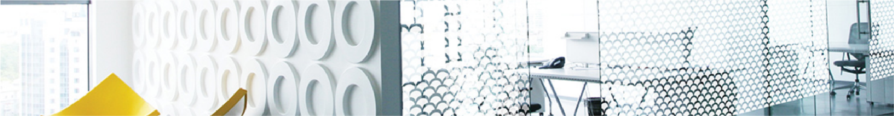 Modern office interior with decorative window film on a glass partition and a desk.