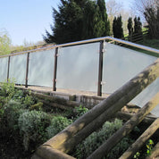 Frosted glass panels on a wooden fence with garden and trees in the background
