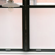 Close up of frosted vinyl on a glass window with a black frame and a light in view