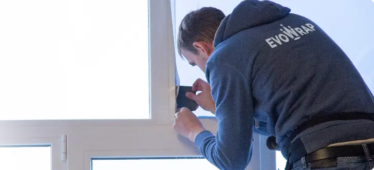Evowrap installer fitting window tint to a house window