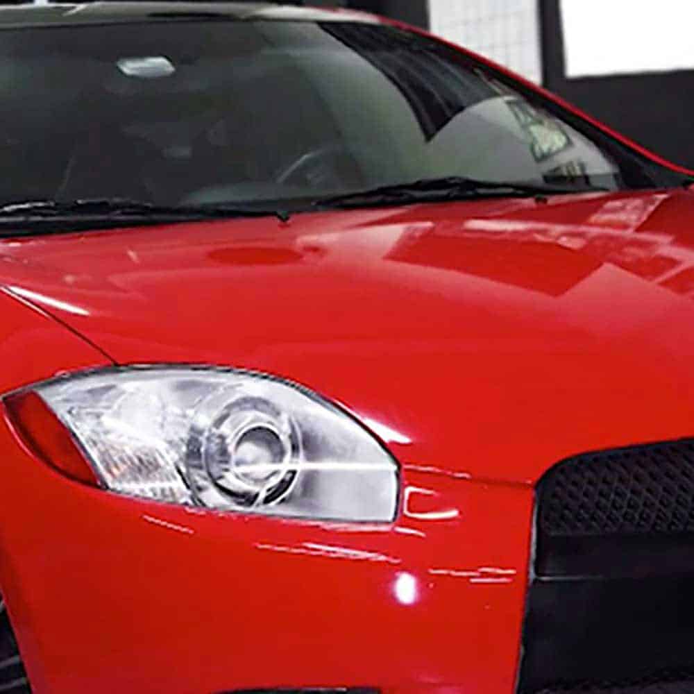 Close-up of the Oracol Gloss Cardinal Red car on the front headlight and grille