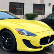 Oracal Gloss Crocus Yellow Maserati car parked in front of a building with glass windows