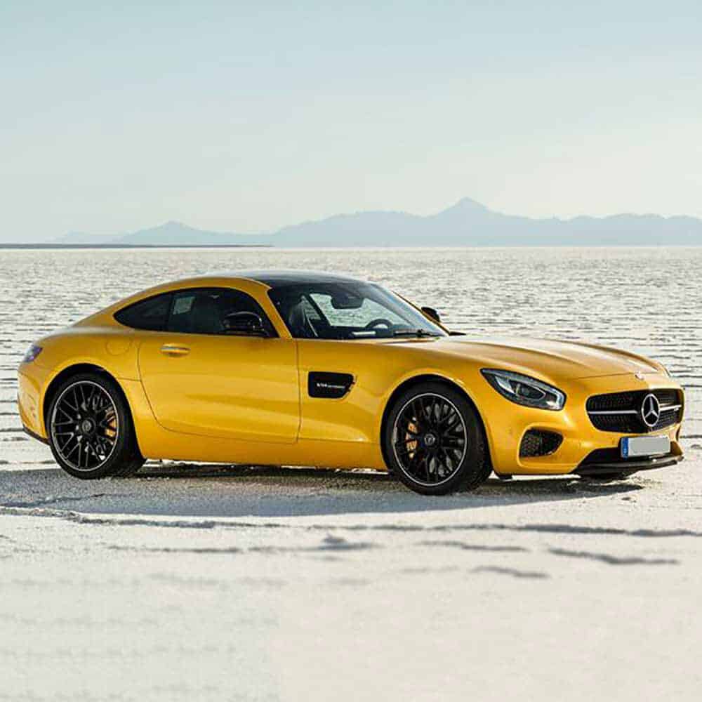 Gloss Maize Yellow Mercedes-Benz sports car on a desert road with mountains