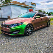Oracal Gloss Avocado car parked on a gravel driveway beside a building 