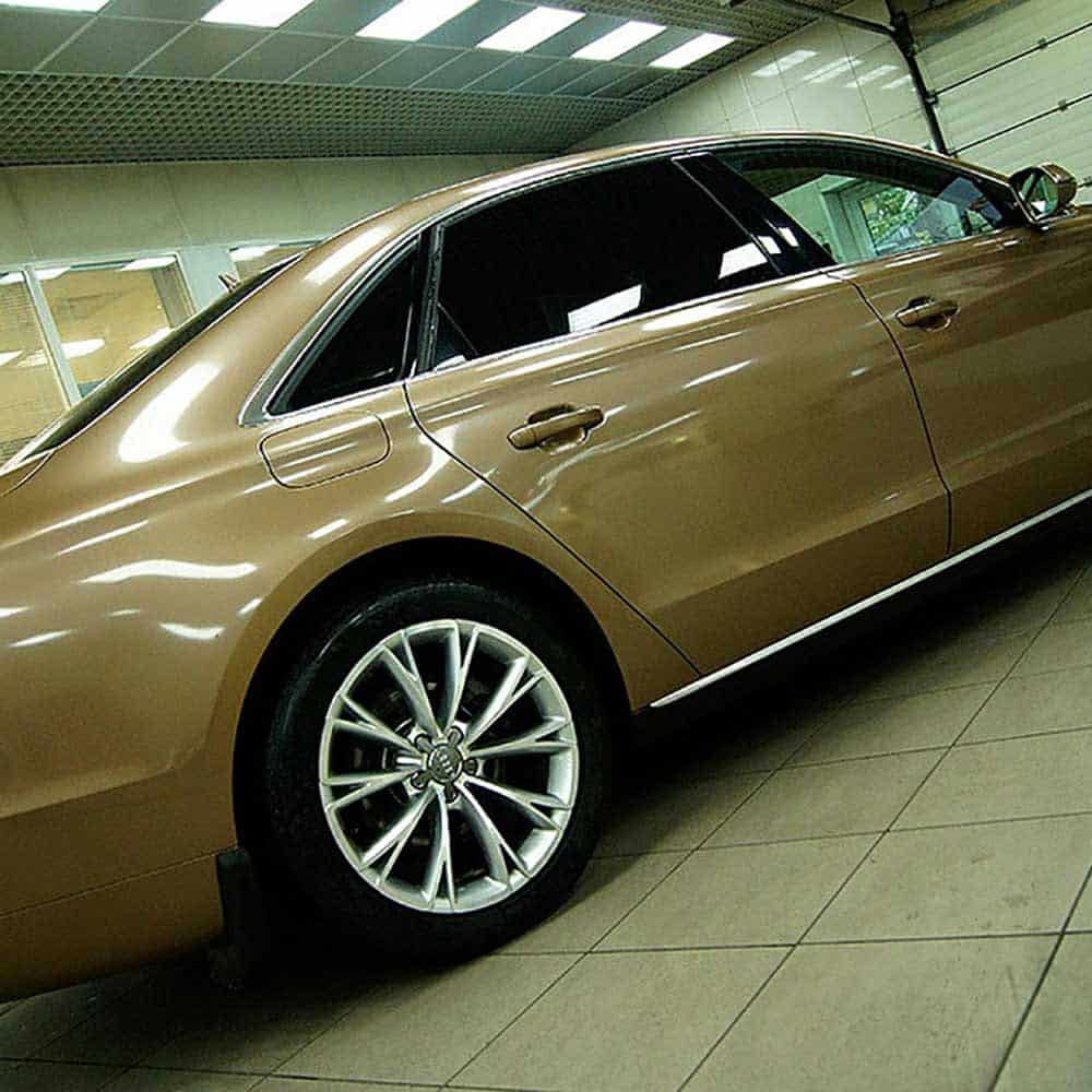 Oracal Gloss Brass Metallic car parked inside a showroom with tiled floor and ceiling lights