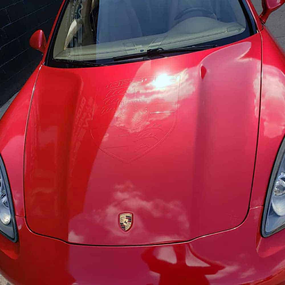 Close-up of an Oracal Gloss Luscious Lips installed on a car with a clear sky reflection on the hood