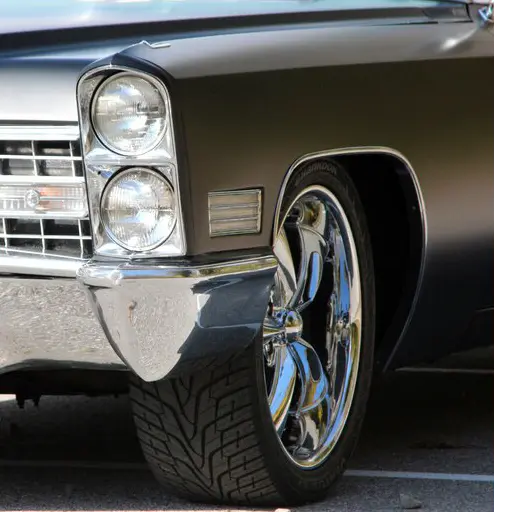 Close-up of a classic car's front wheel and headlight with Oracal super matt black vinyl wrap installed