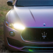 Close-up of a Maserati wrapping in Oracal 970-315M matte pearl symphony car wrap with its headlights on, parked outdoors.