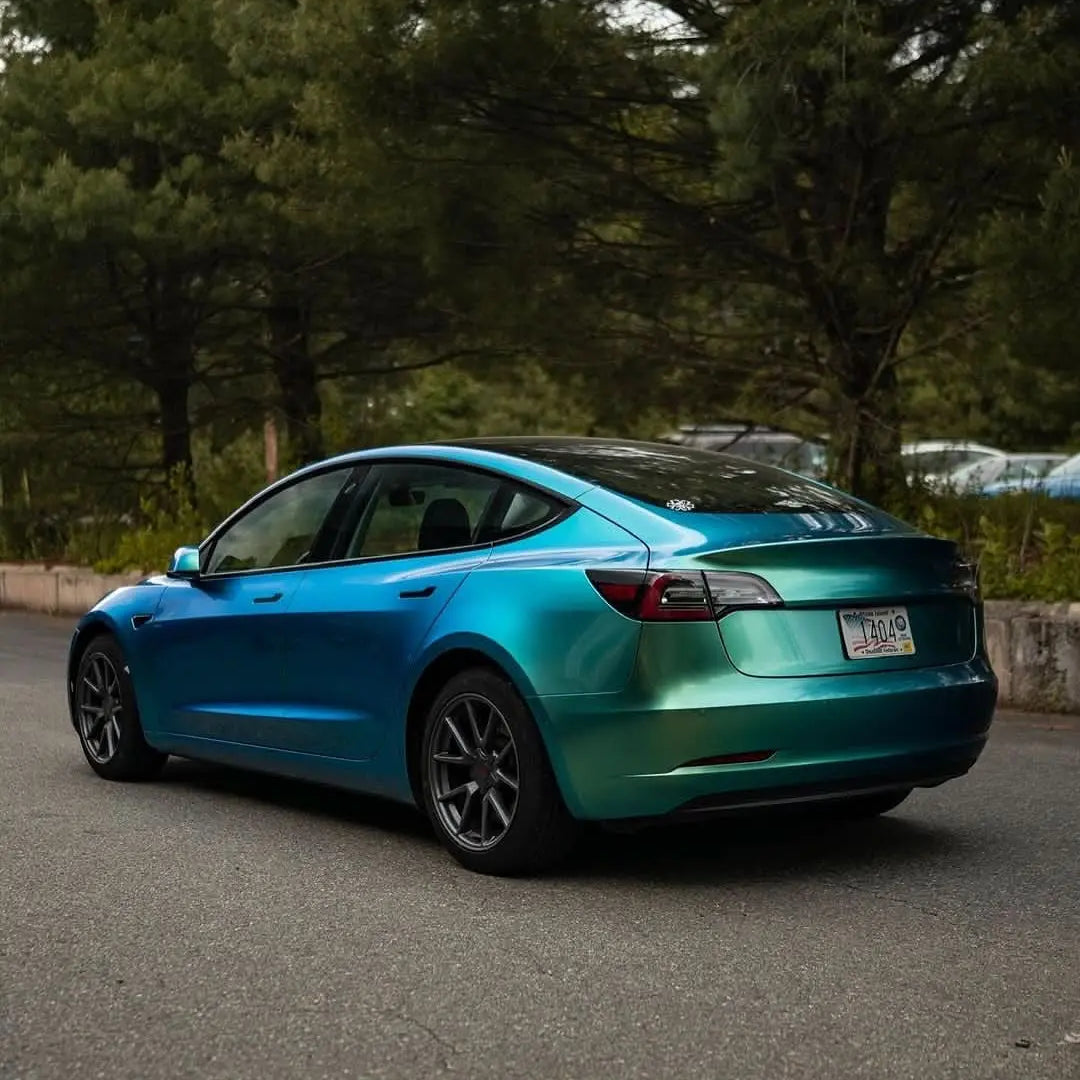 Oracal Gloss Aquamarine installed on a Tesla car parked on a road with trees