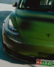 Close-up of a Oracal Gloss Bottle Green Tesla car on a road