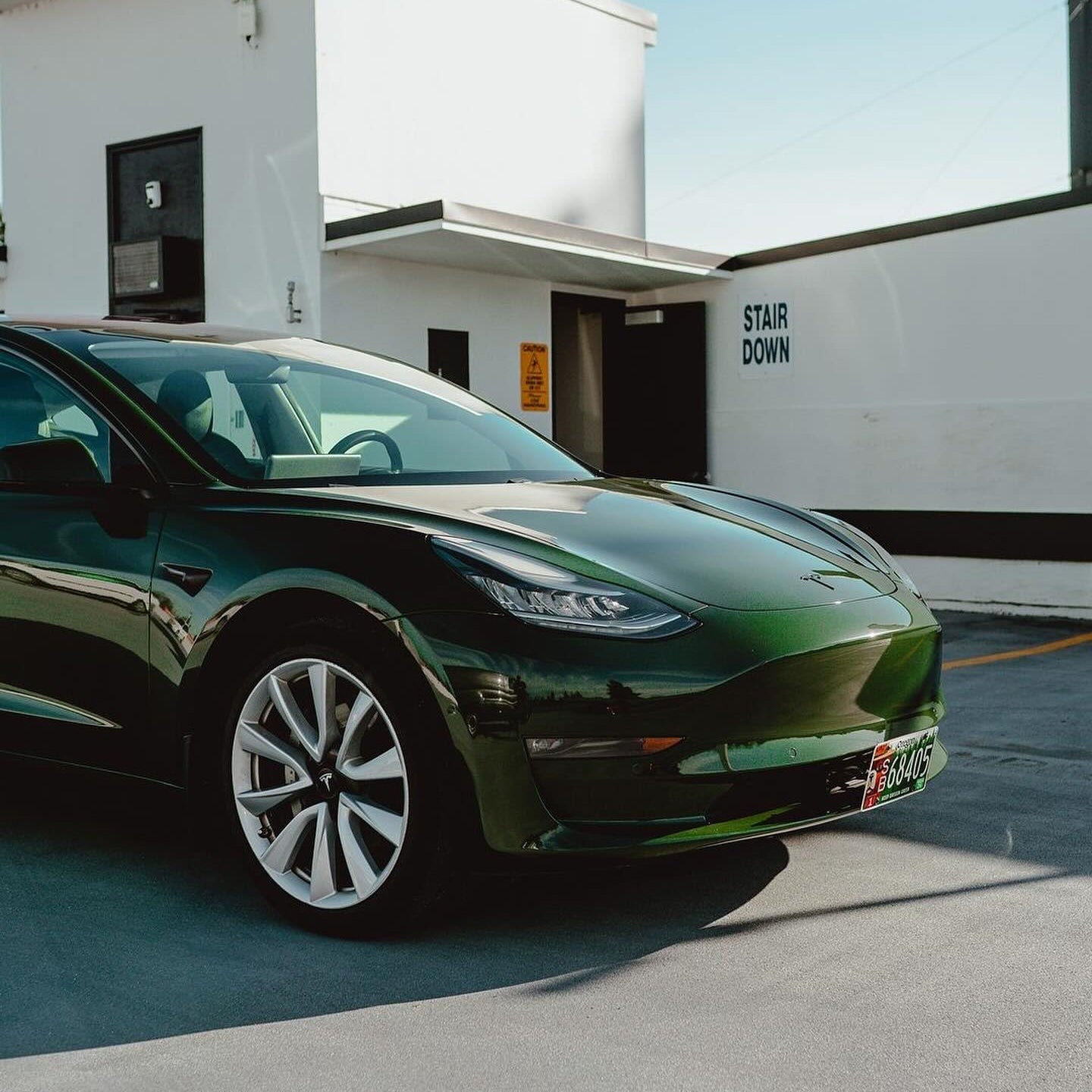 Oracal Gloss Bottle Green Tesla car parked in front of a building with 'Stair Down' sign