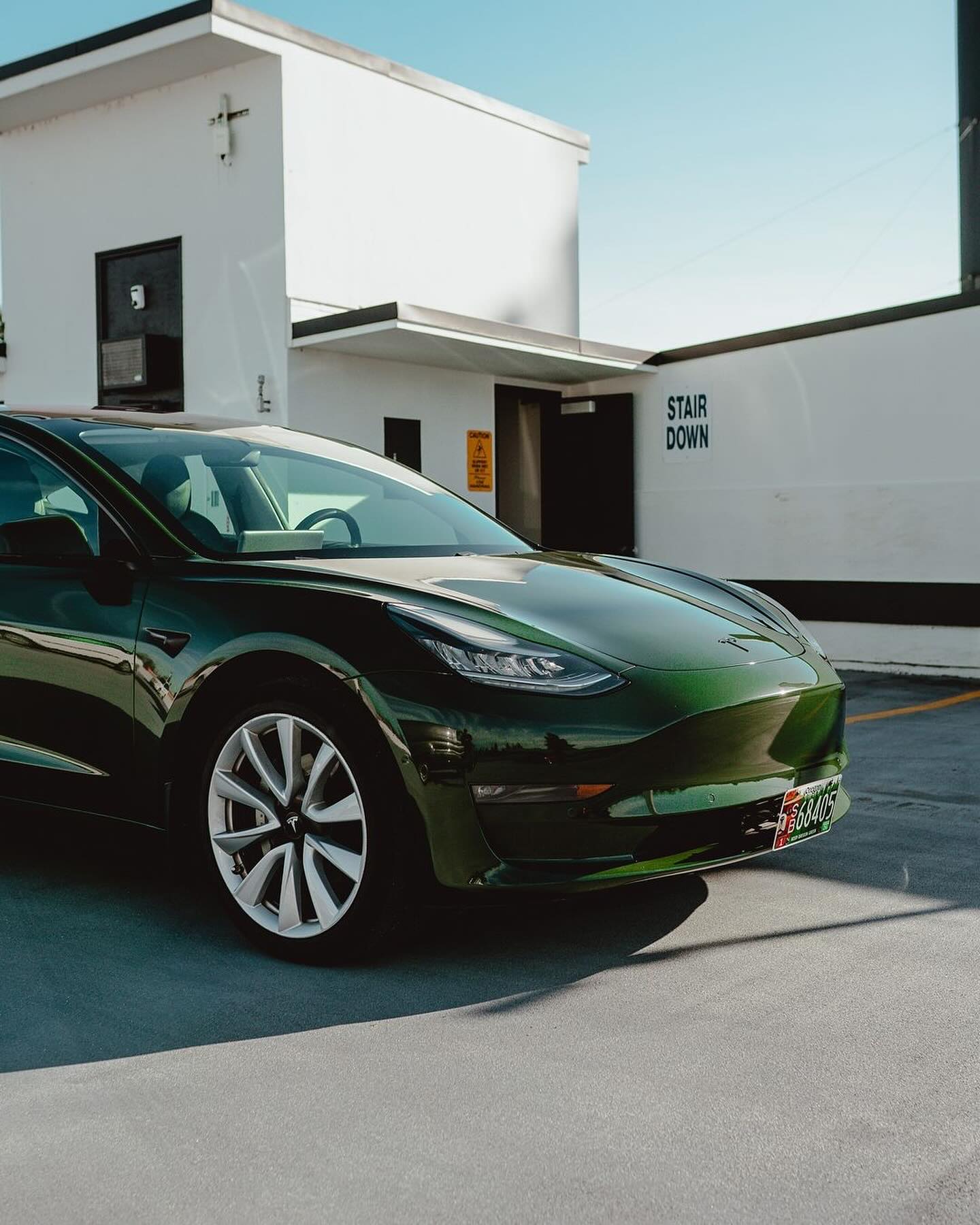 Oracal Gloss Bottle Green Tesla car parked in front of a building with 'Stair Down' sign