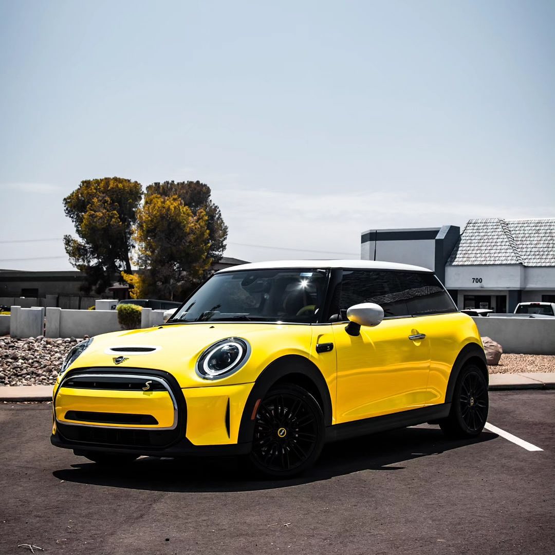 Oracal Gloss Canary Yellow wrap installed on a Mini Cooper, parked on a street with trees and buildings