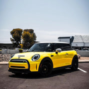 Oracal Gloss Canary Yellow wrap installed on a Mini Cooper, parked on a street with trees and buildings