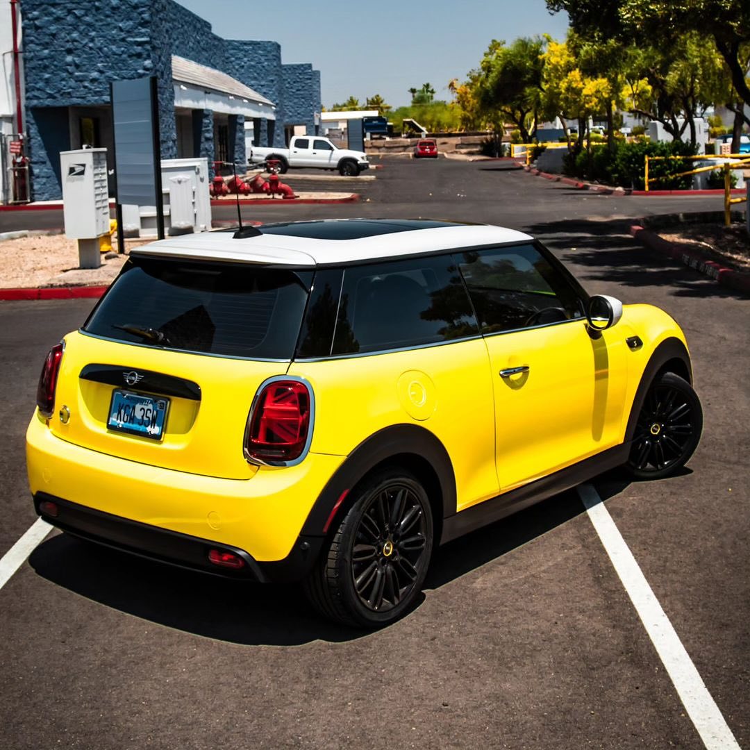 Oracal Gloss Canary Yellow wrap installed on a Mini Cooper car parked on a street with buildings and trees