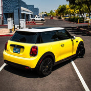 Oracal Gloss Canary Yellow wrap installed on a Mini Cooper car parked on a street with buildings and trees