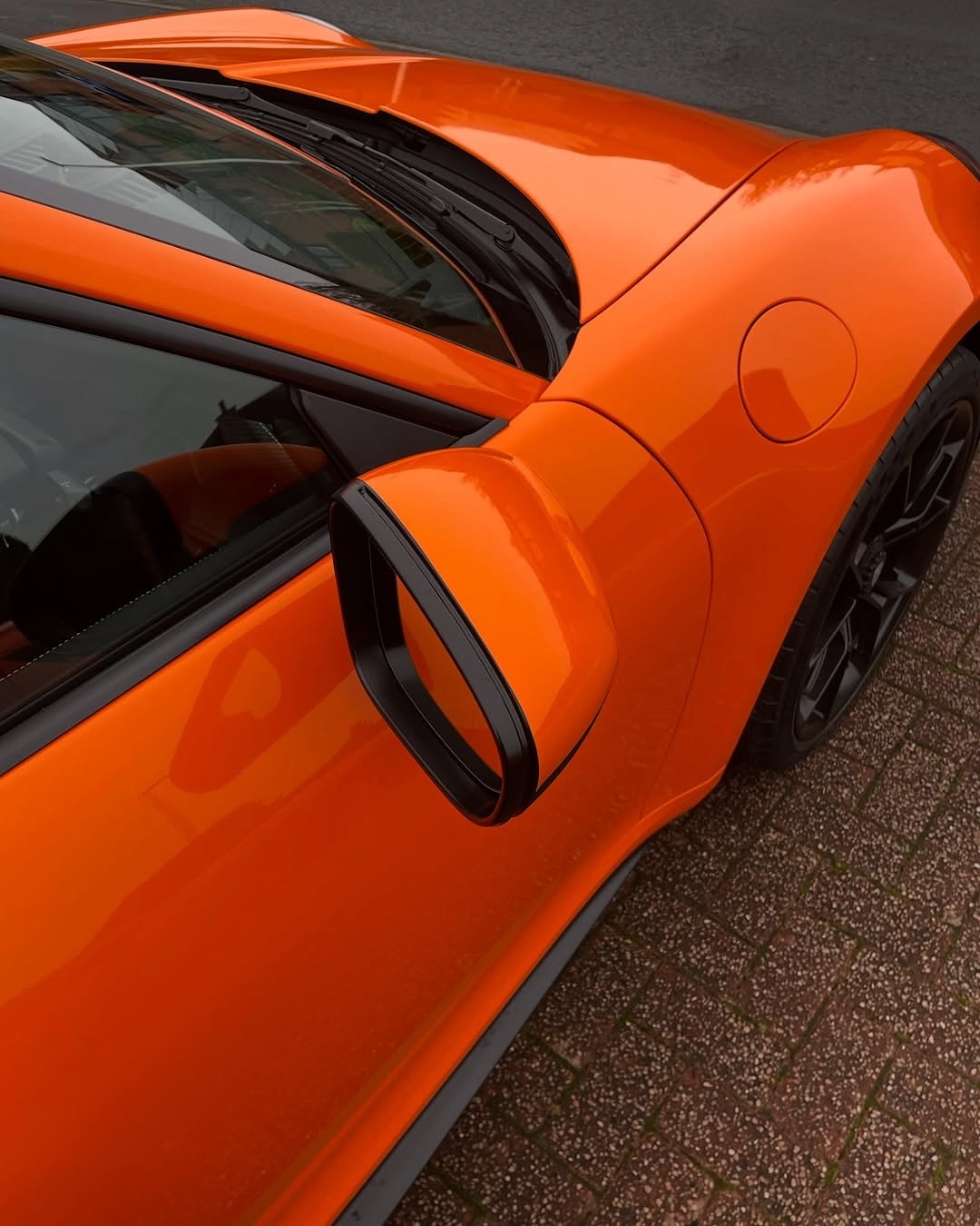 Close-up of an Oracal Gloss Daggi Orange sports car on a textured surface
