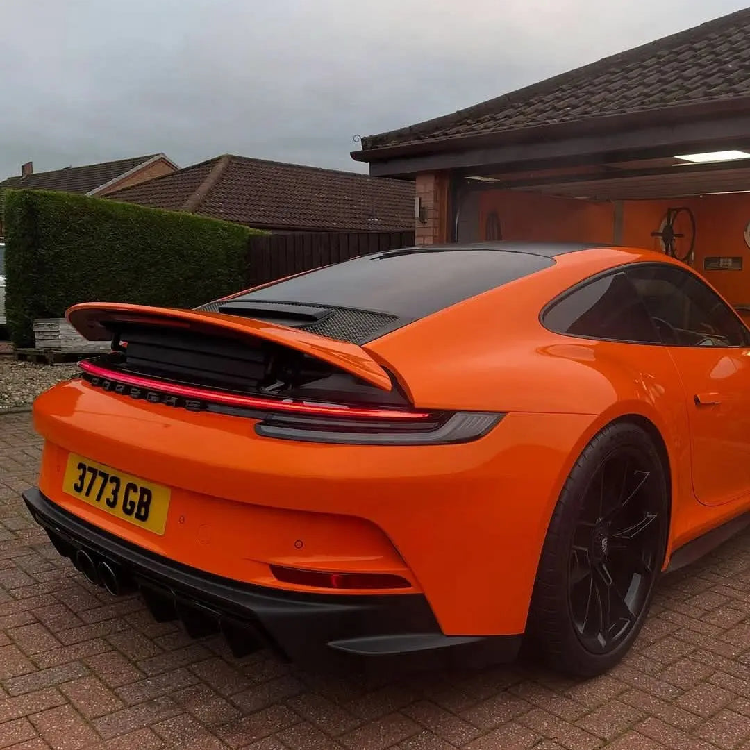 Oracal Gloss Daggi Orange sports car parked on a driveway with a house