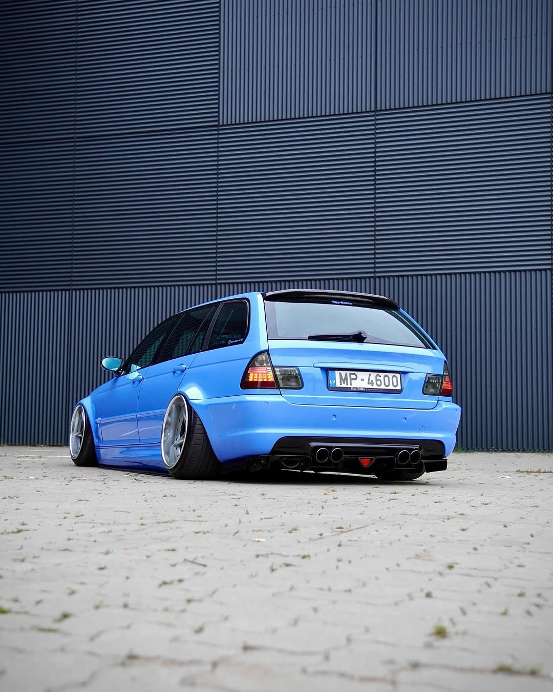 Rear view of Oracal Gloss Glacier Blue installed on a car parked in front of a blue metallic wall