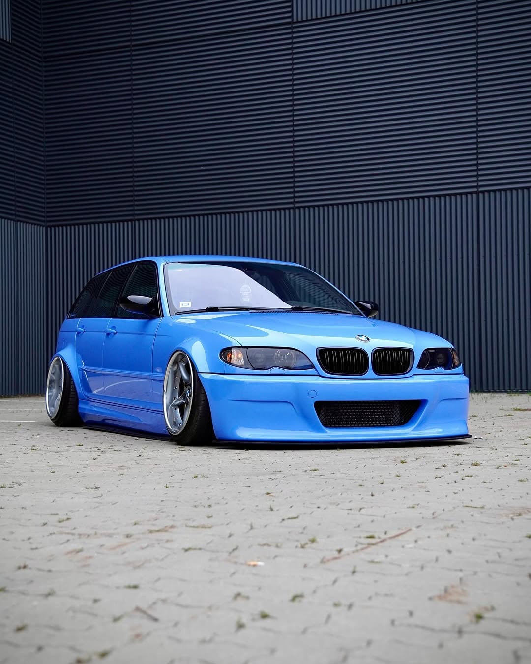Oracal Gloss Glacier Blue installed on a BMW car parked in front of a dark metallic wall