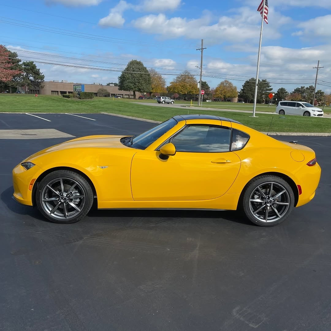 Oracal Gloss Golden Yellow installed on a car parked on a paved surface with a grassy area and trees