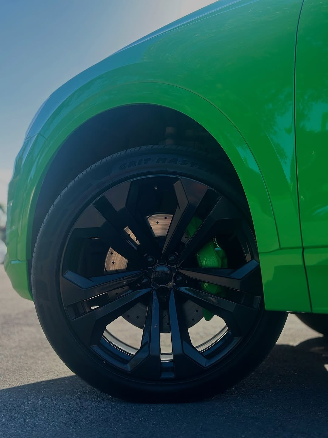 Close-up of an Oracal Gloss Grass Green car with black alloy wheels on a clear day