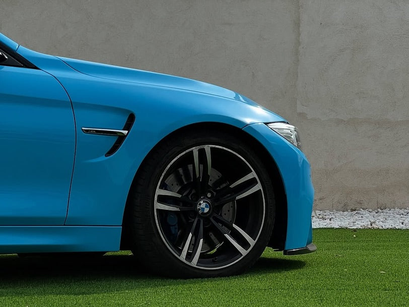Side view of Oracal Gloss Ice Blue installed on a car with black rims on a grassy surface