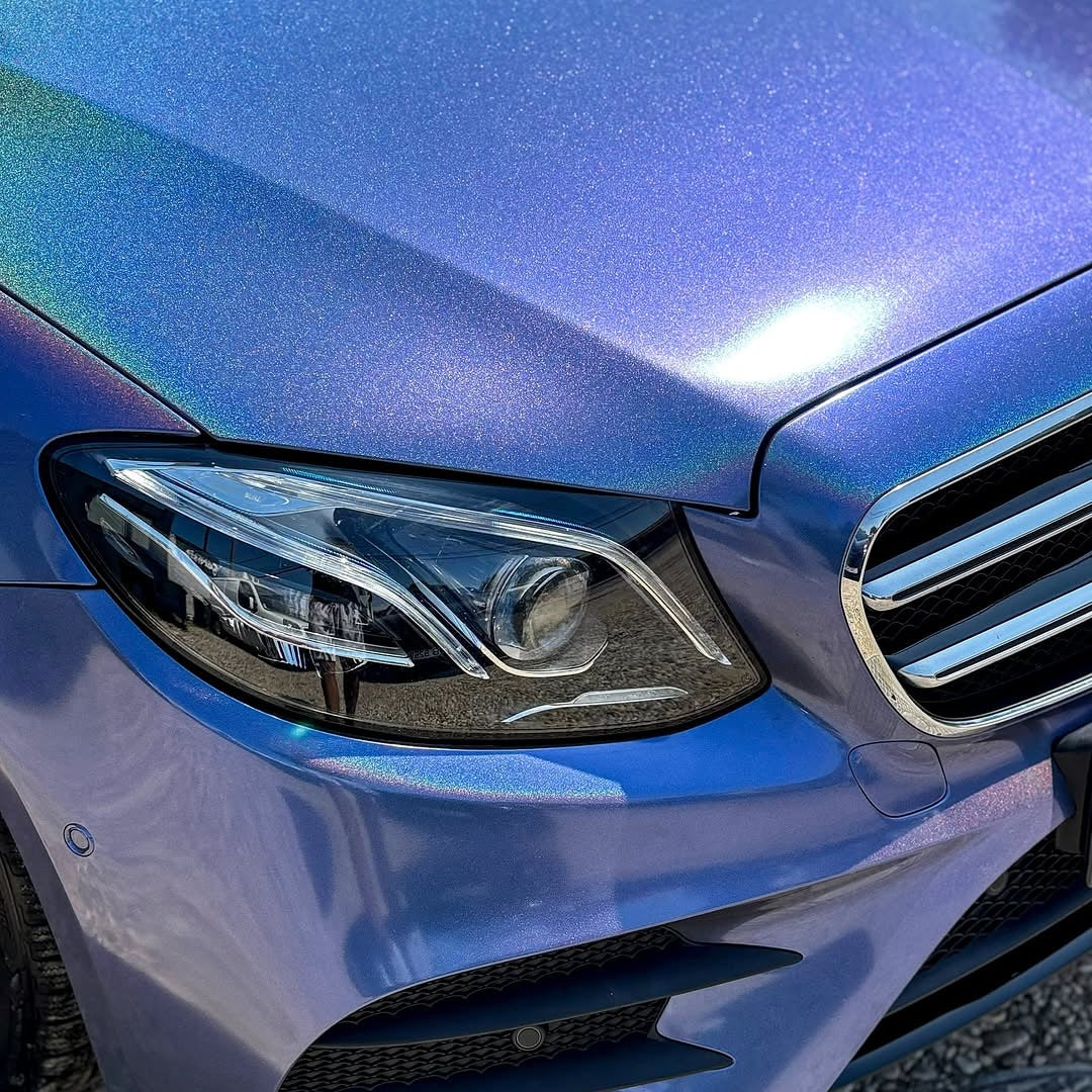 Close-up of a blue car's headlight and grille with Gloss Intergalactic Blue installed