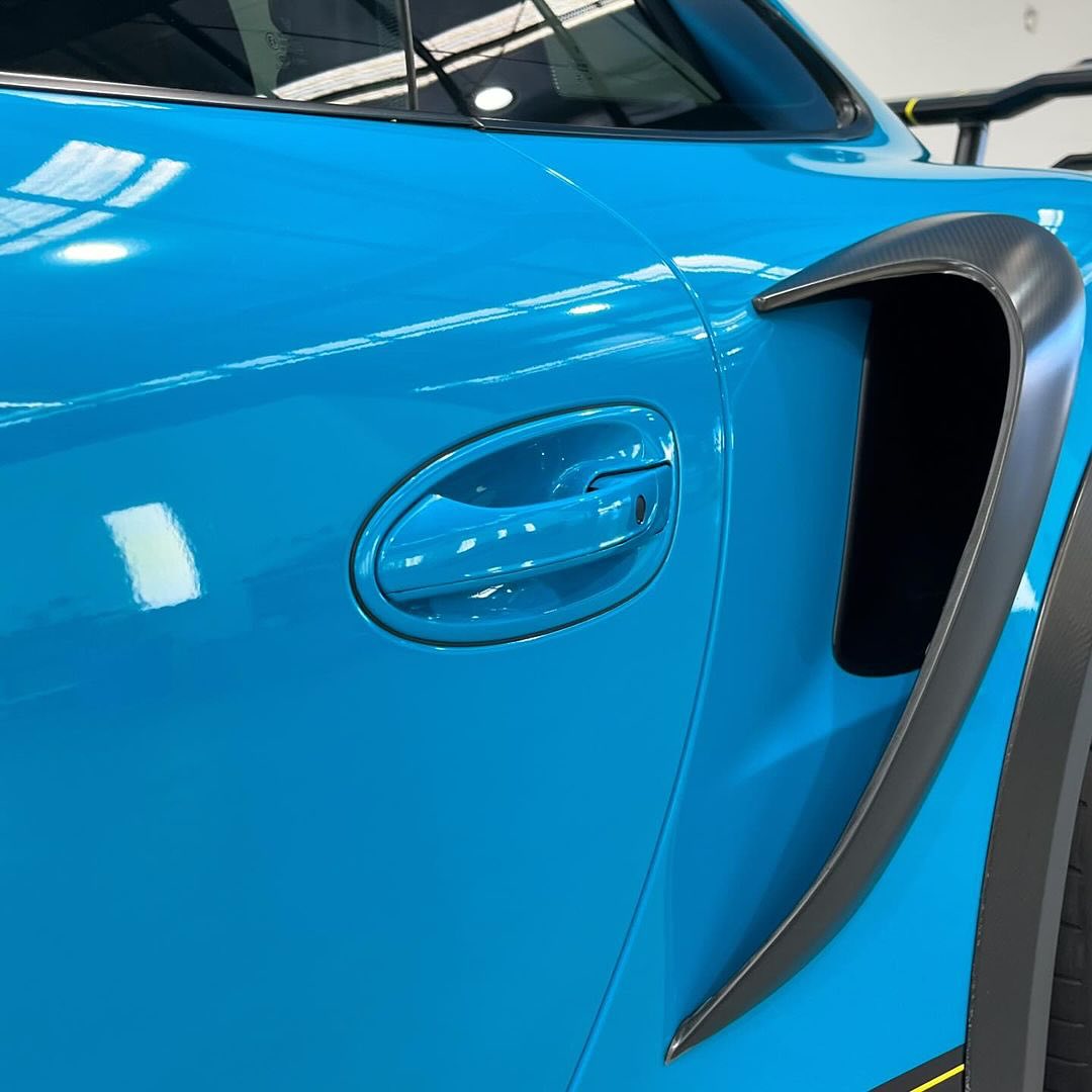 Close-up of an Oracal Gloss Lagoon car door with a black door handle and trim