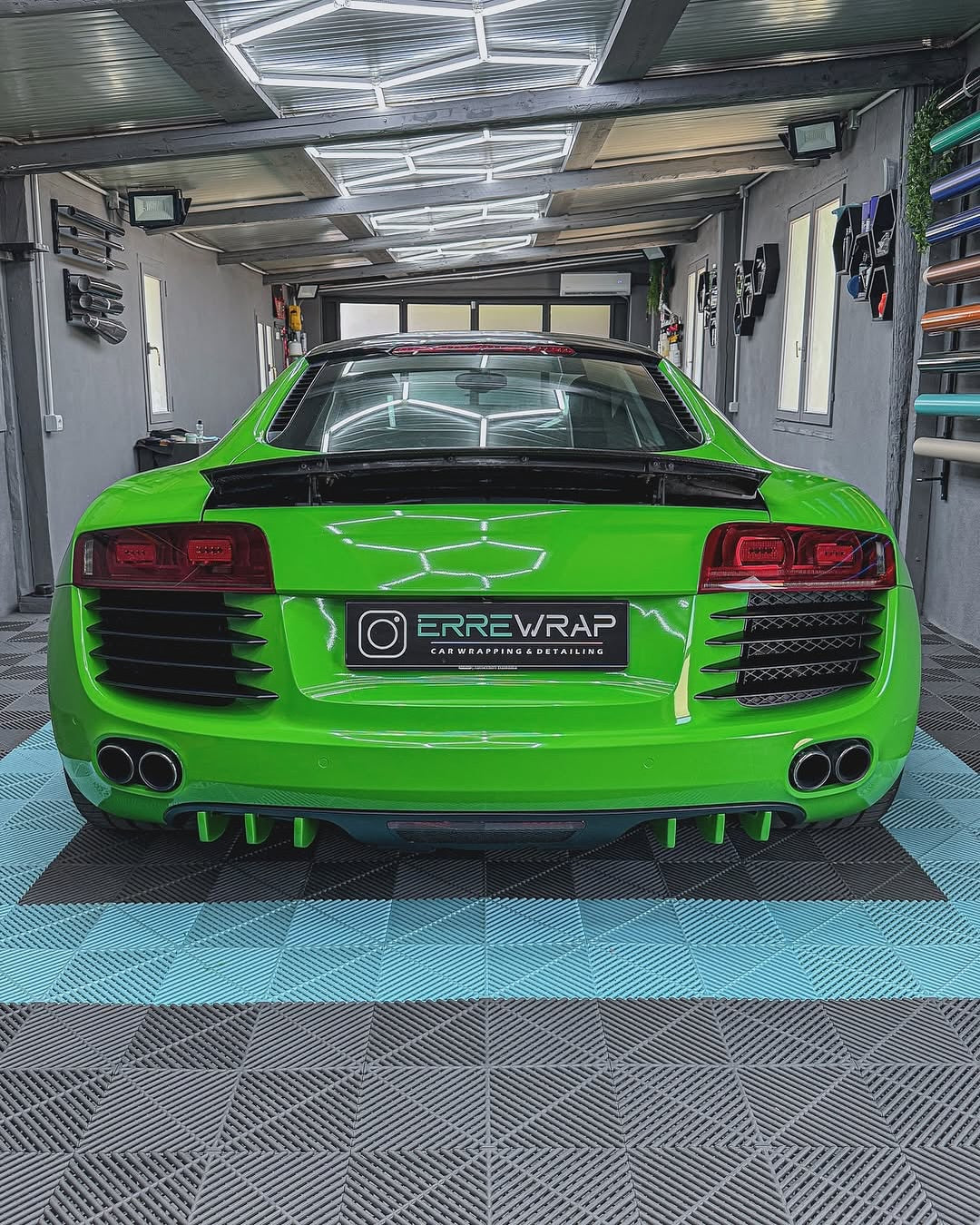 A sports car with an Oracal Gloss Lawn Green cover is parked in a garage