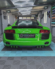 A sports car with an Oracal Gloss Lawn Green cover is parked in a garage