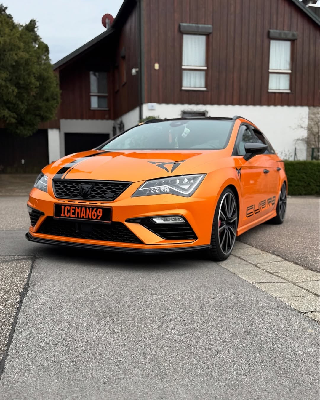 A car with Oracal Gloss Mandarin Metallic installed is parked on a street.