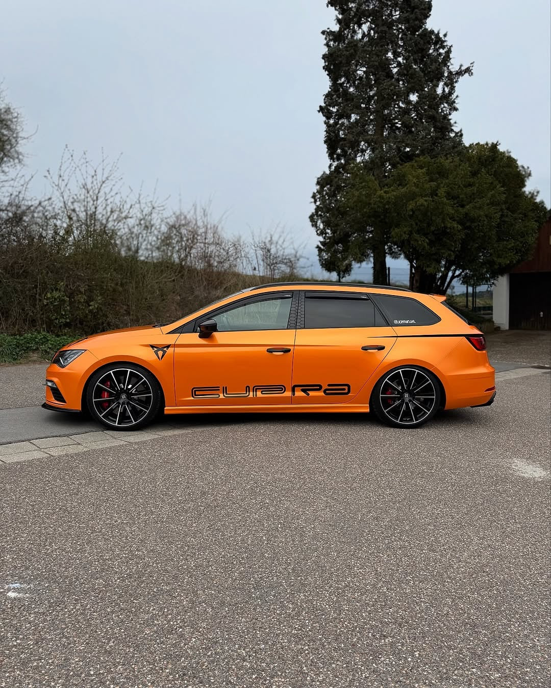 A car with Oracal Gloss Mandarin Metallic installed on a road with trees