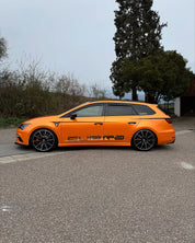 A car with Oracal Gloss Mandarin Metallic installed on a road with trees
