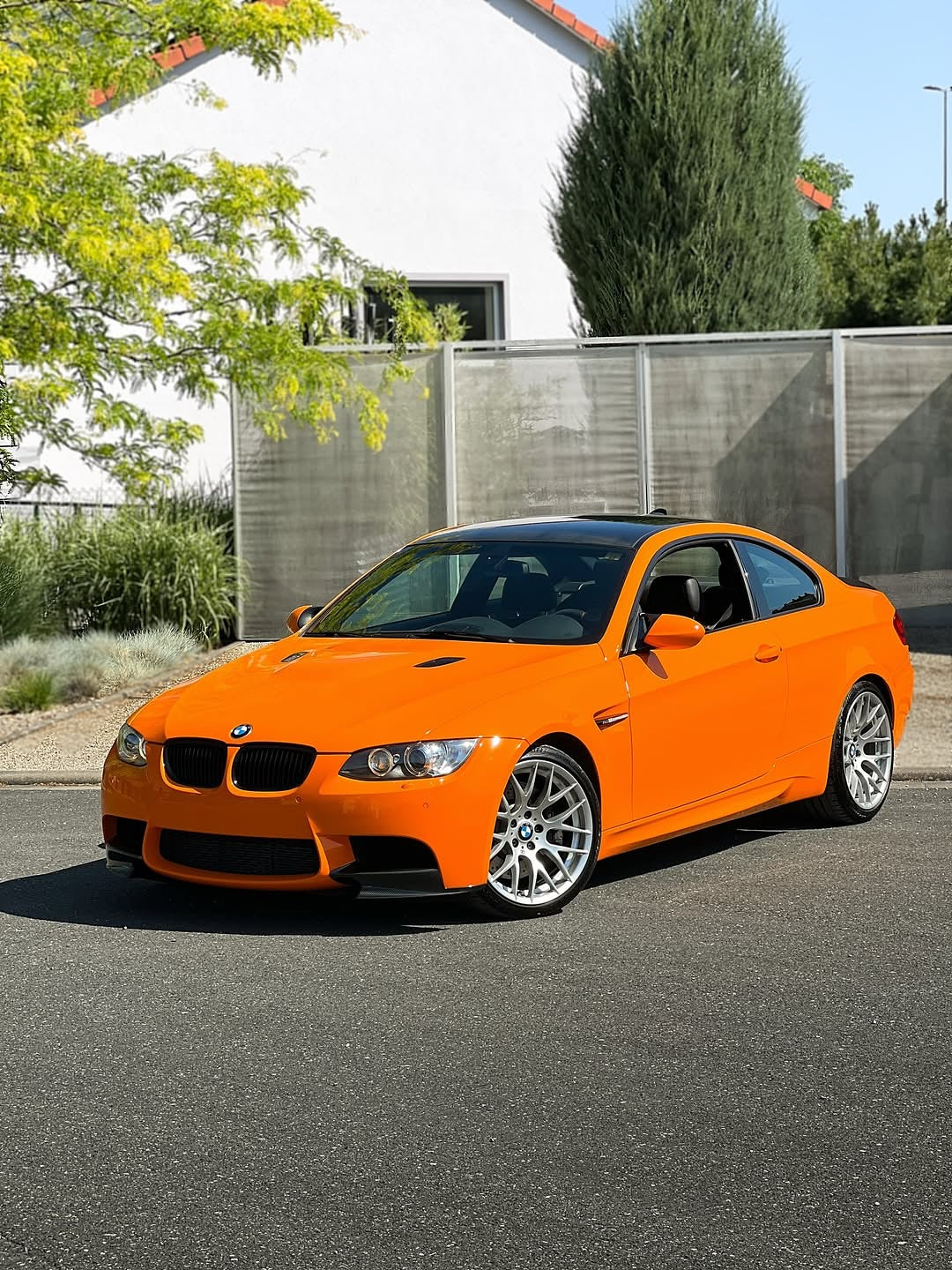 Oracal Gloss Municipal Orange on a BMW car parked on a street with a white building and trees