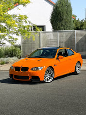 Oracal Gloss Municipal Orange on a BMW car parked on a street with a white building and trees