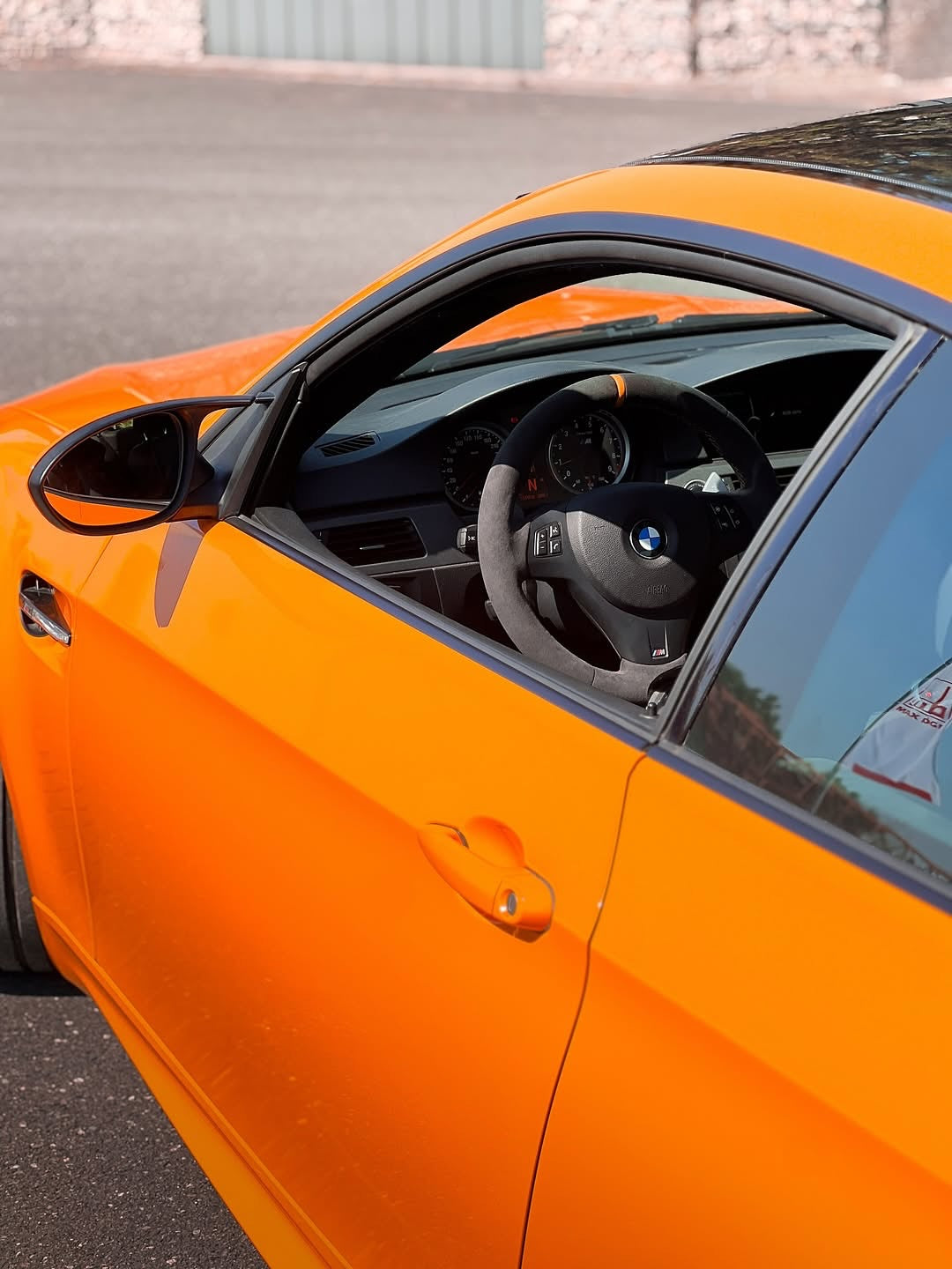 Close-up of an Oracal Gloss Municipal Orange car's interior with a steering wheel and dashboard