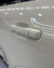 Close-up of a car door handle and window control panel with Oracal Gloss Papyrus installed