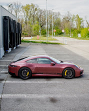 Oracal Gloss Red Brown Metallic installed on a Porsche car parked on a street with trees and buildings