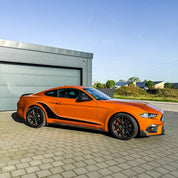 Oracal Gloss Tangerine Dream sports car parked on a paved area with a building and greenery