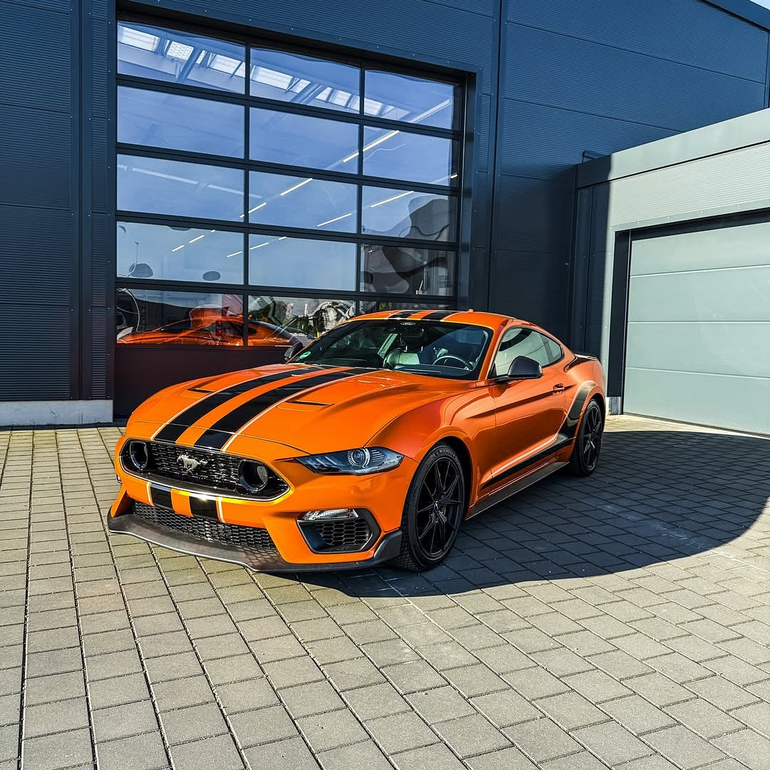 Oracal Gloss Tangerine Dream on Mustang, parked in front of a modern building
