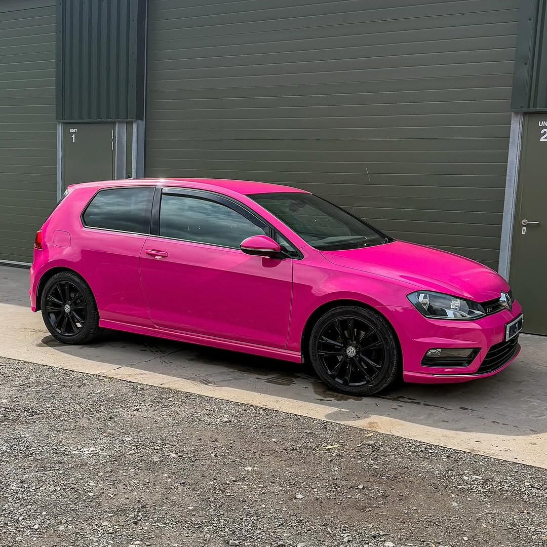 Oracal Gloss Telemagenta installed on a Volkswagen and parked in front of a gray garage door