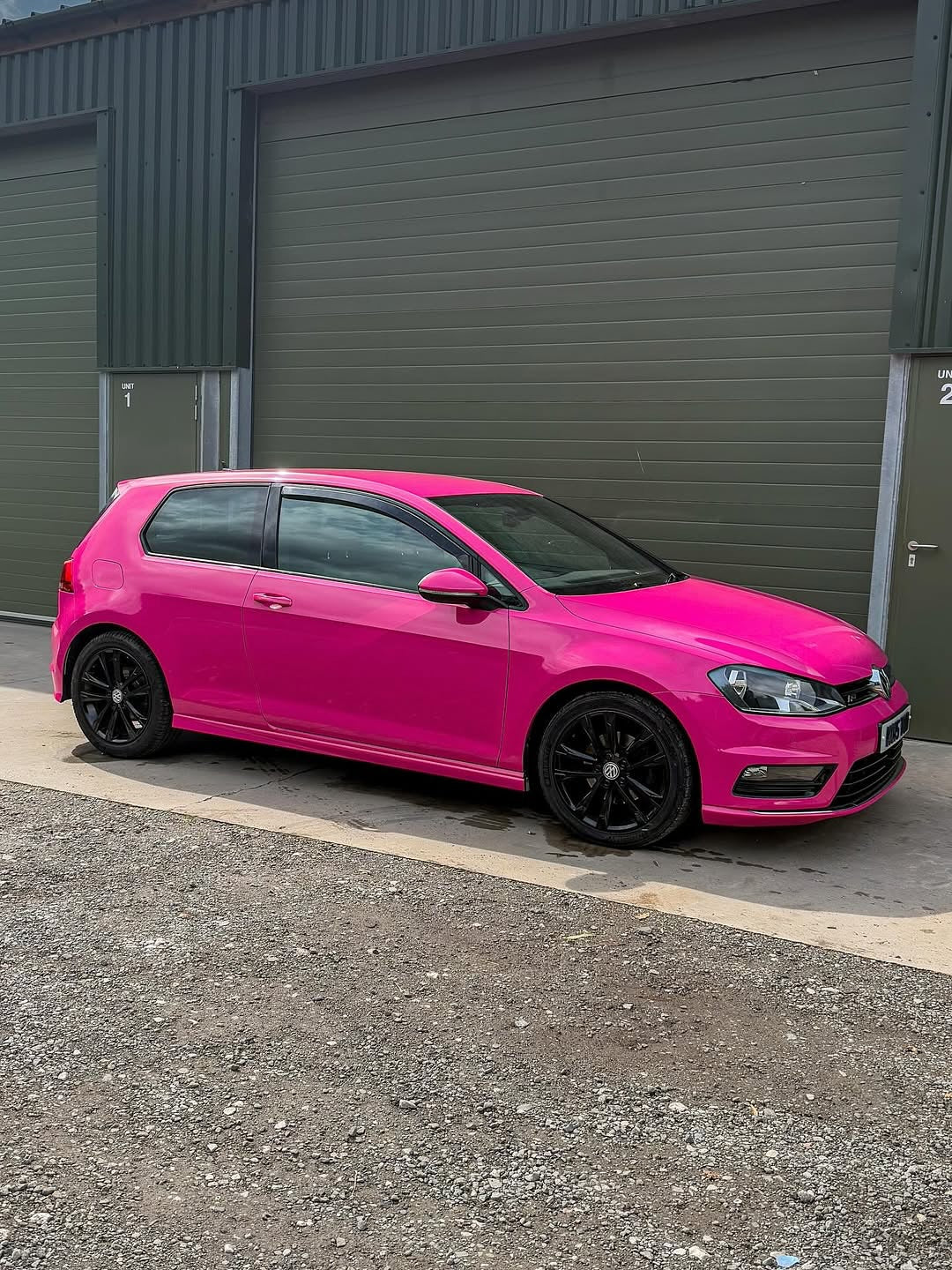 Oracal Gloss Telemagenta installed on a Volkswagen and parked in front of a gray garage door