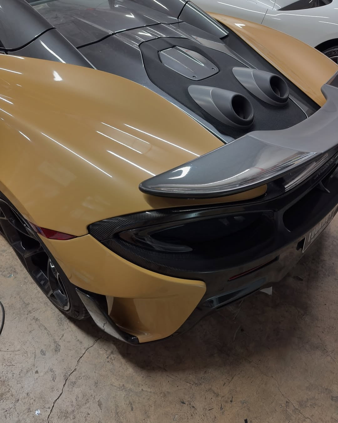 Close-up of a car's front bumper and hood in a garage with Oracal Gloss Turquoise Lavender installed