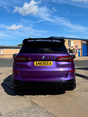 Close-up rear view of Oracal Gloss Violet Metallic wrap on a BMW car with a yellow license plate on a clear day